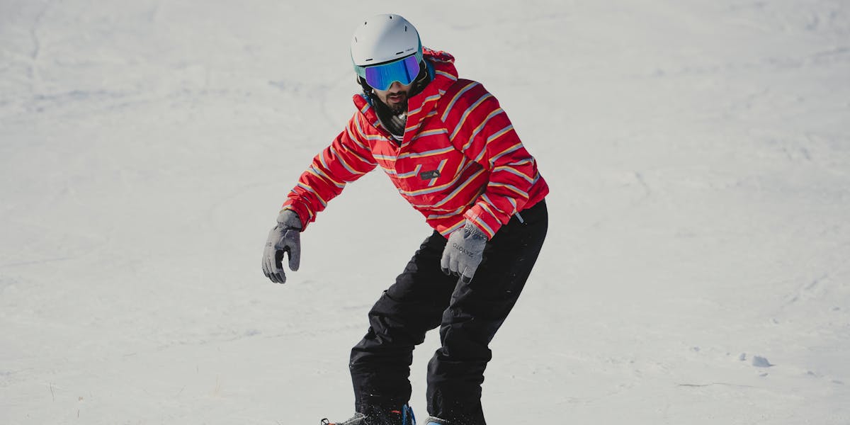 A snowboarder wearing a red jacket glides down a snowy slope, capturing winter a