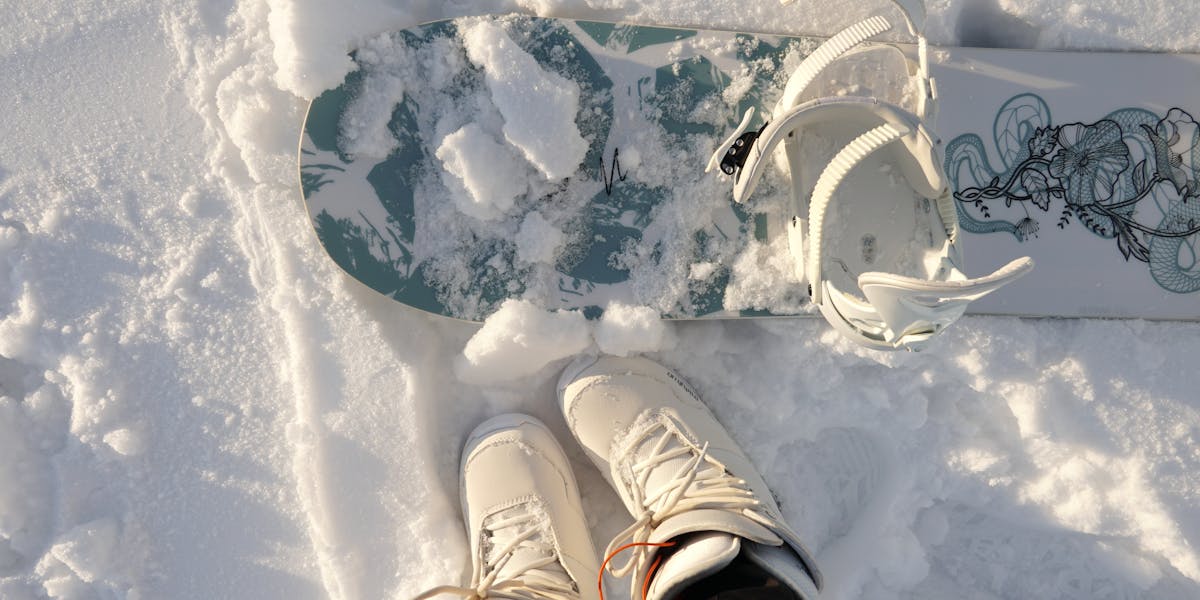 Top view of snowboard and boots in fresh snow, capturing the essence of winter spo...