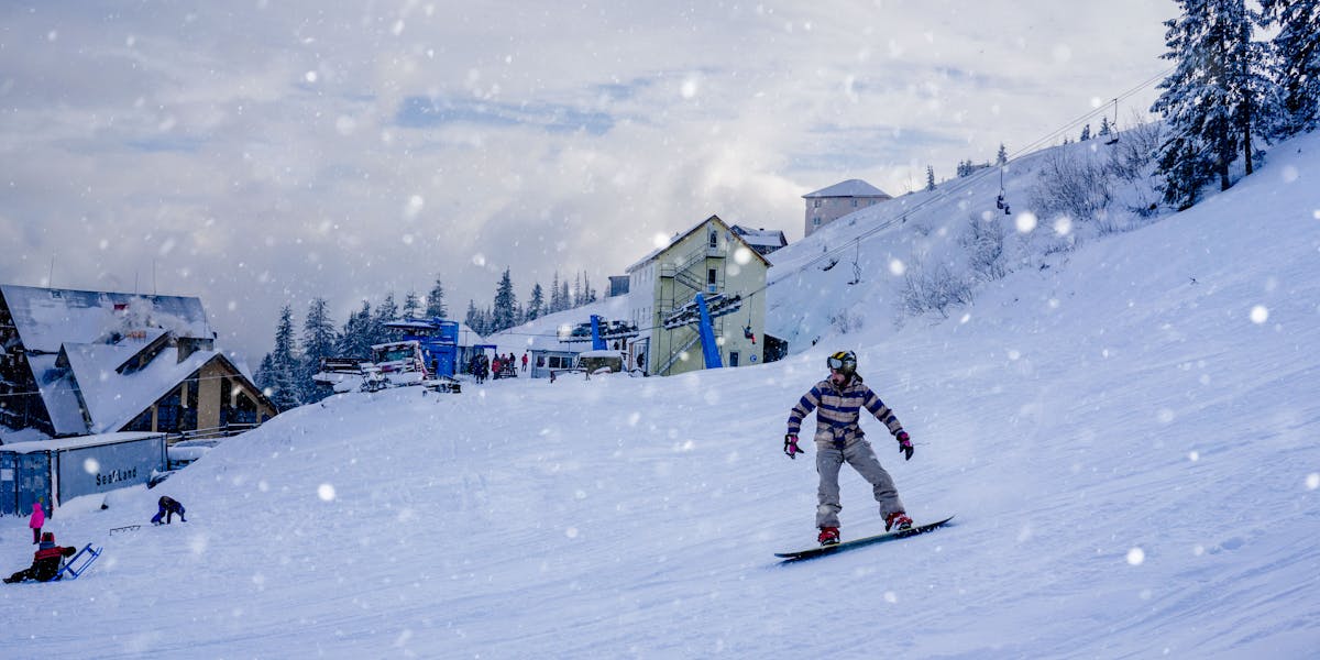 A snowboarder skillfully carves through fresh snow on a winter day, capturing th