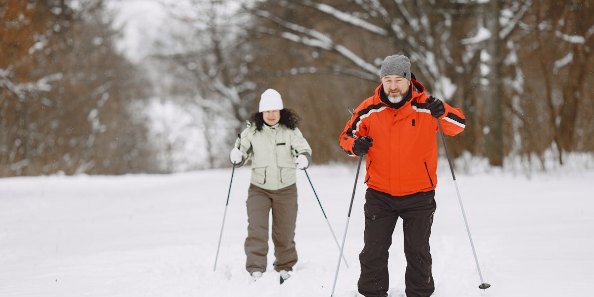 A man and a woman skiing through a snowy forest, enjoying a winter outing in war