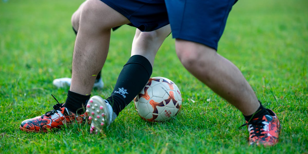 Close-up of two soccer players competing for the ball on a grassy field.