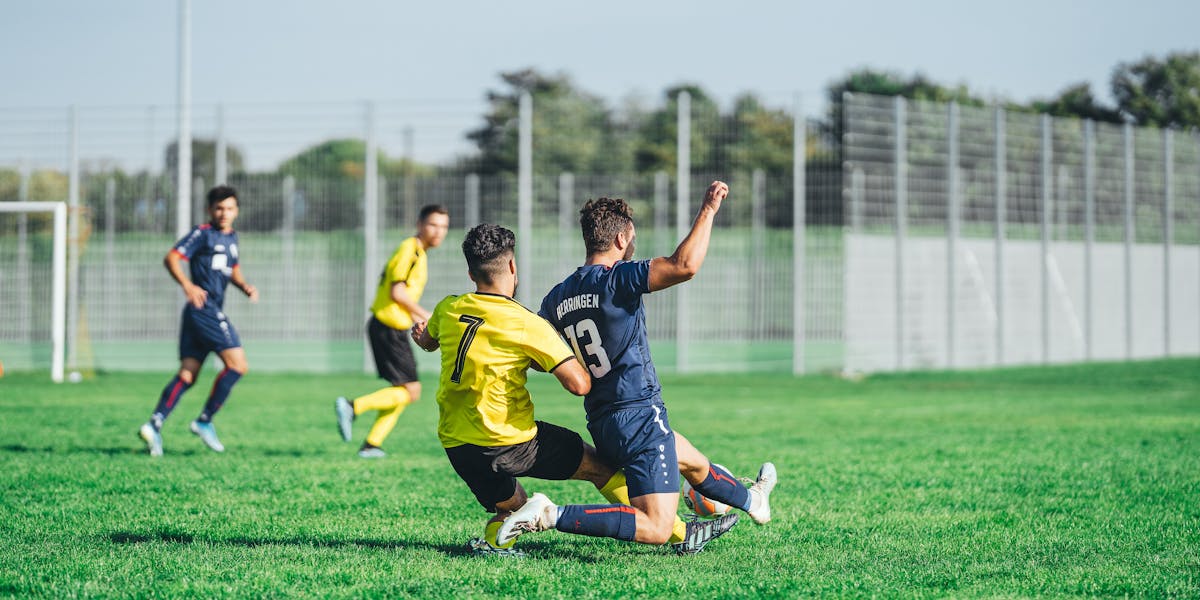Soccer goalkeeper in action holding ball on sunny field during a game.