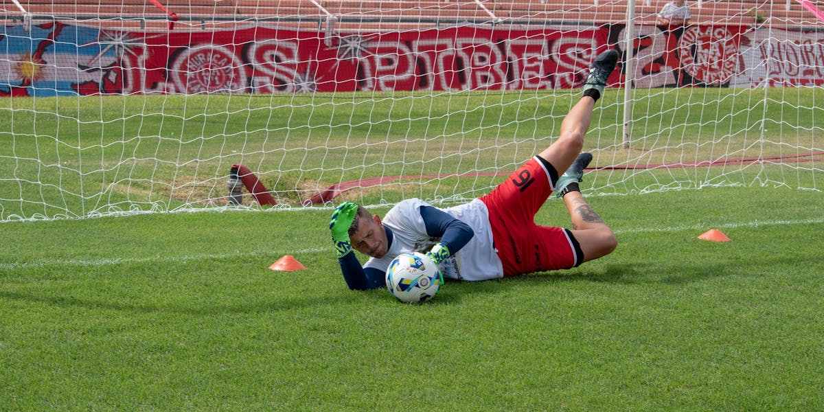 A goalkeeper in action making a dive save during a football practice session on a ...