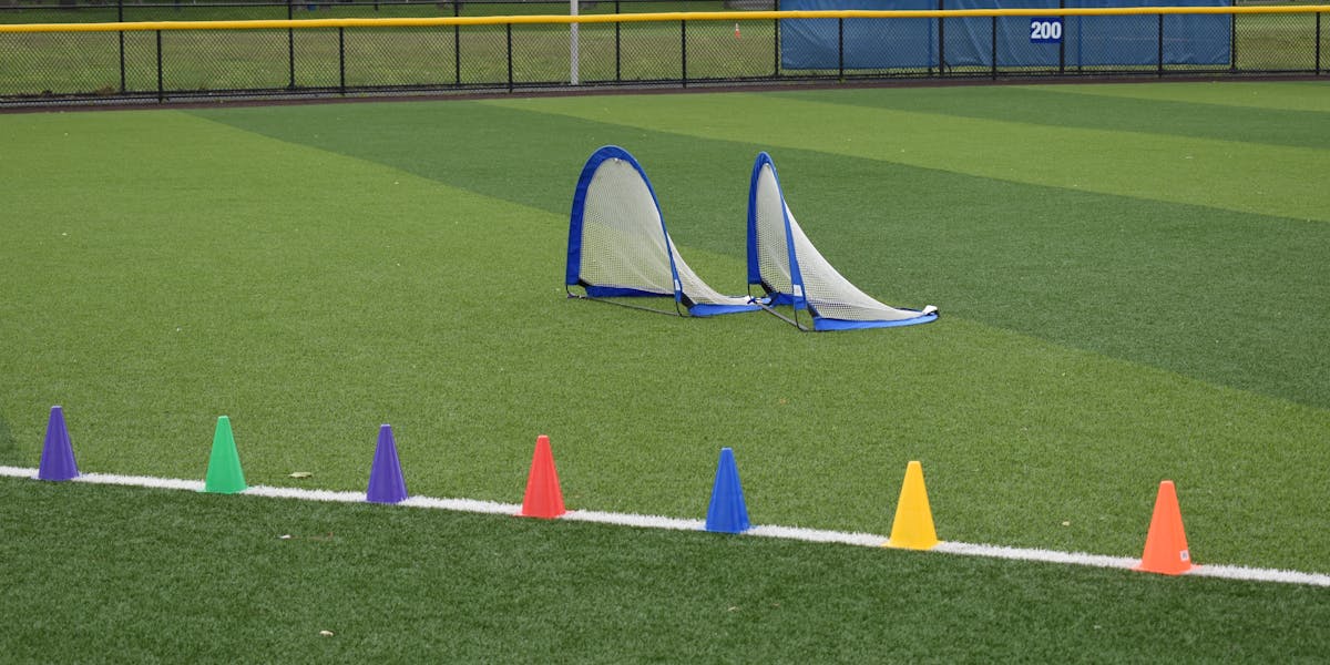 Colorful training cones and soccer nets on an empty sports field.