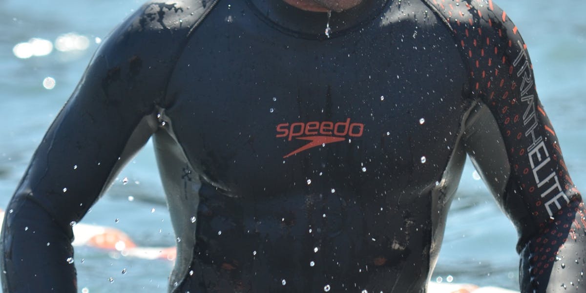 Focused swimmer emerges from water in sleek wetsuit and vibrant swim cap.