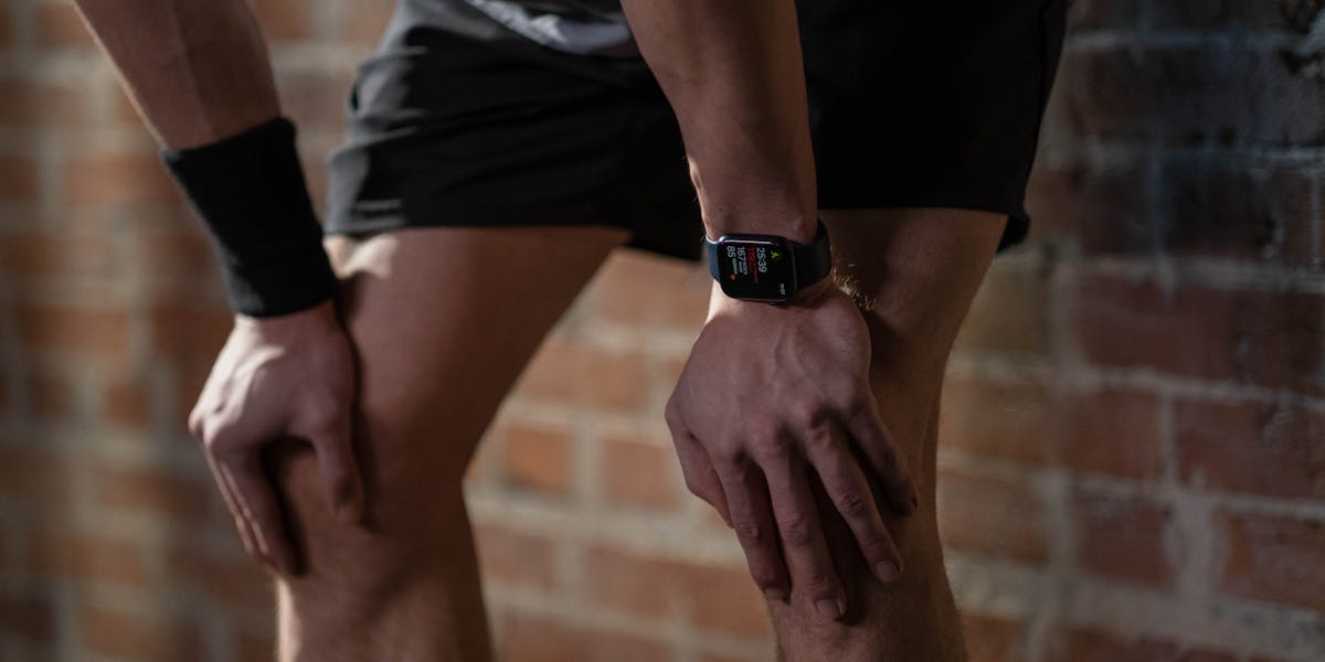 Close-up of a cyclist wearing gloves checking a smartwatch outdoors.