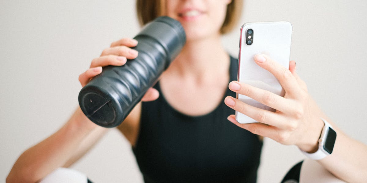 Man exercises with dumbbells and VR headset in a modern gym setting.