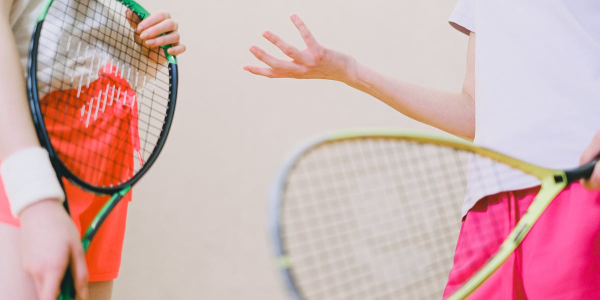 Two tennis players with rackets and a tennis ball, captured in an indoor sports se...