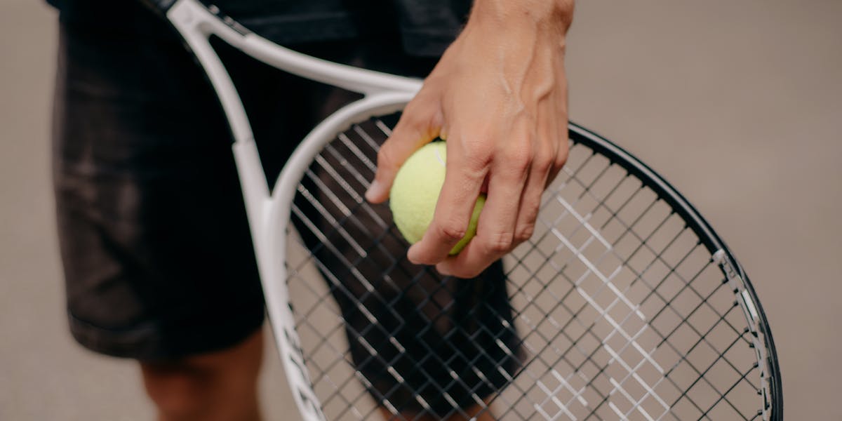 Detailed view of a tennis player holding a tennis ball and racket, preparing for a...