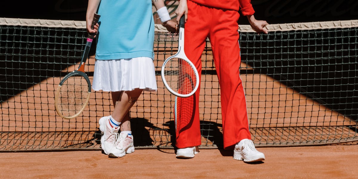 A prosthetic-wearing female tennis player relaxes on the court, embracing the su