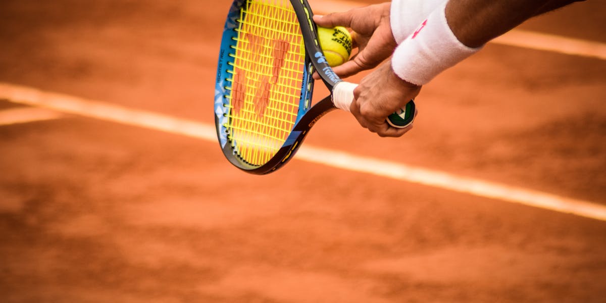 Close-up of a tennis player preparing to serve on a clay court in Montevideo.