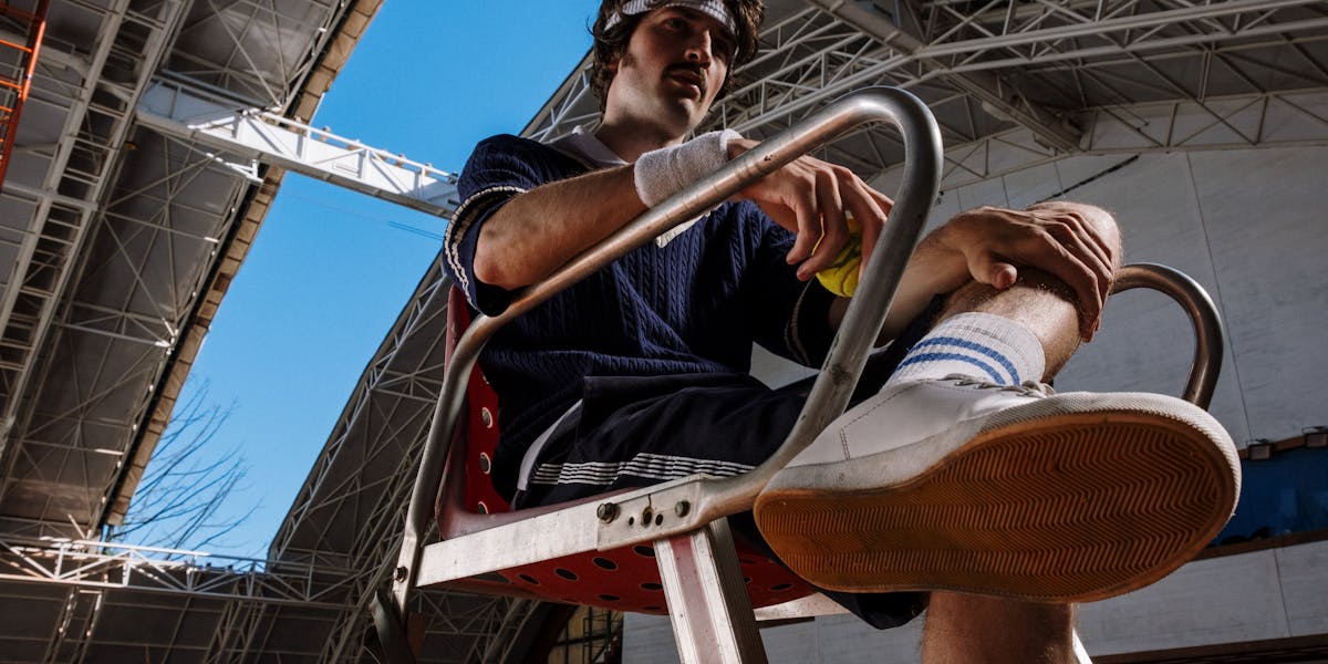 Close-up of a tennis player with racket and ball on a clay court, wearing white sn...