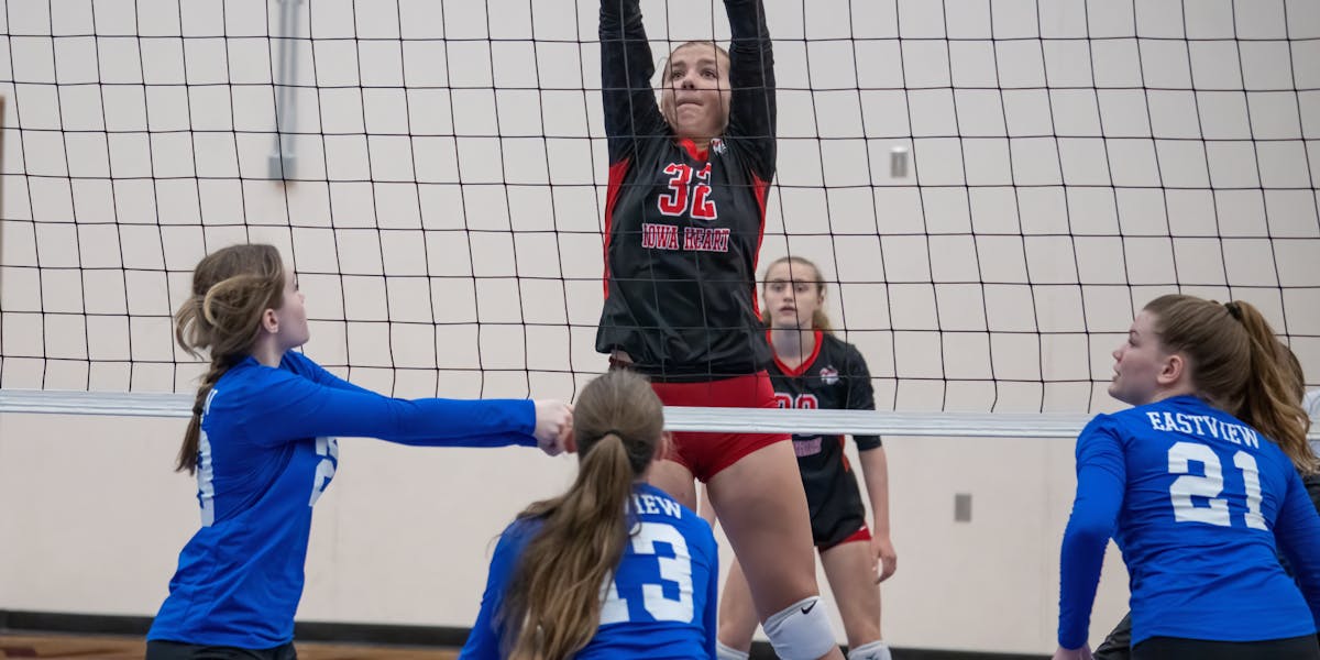 Dynamic action shot from a women's volleyball match with players in mid-air at the...