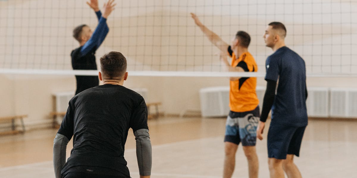 Four men engaged in an indoor volleyball game, showcasing athletic teamwork and 